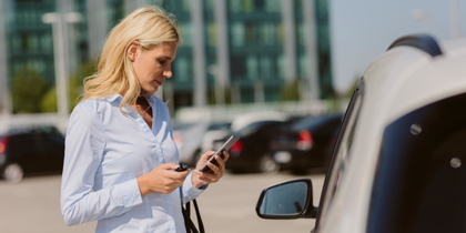 woman standing by car on smartphone