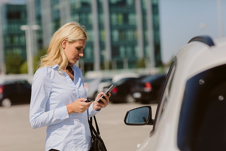 woman standing by car on smartphone